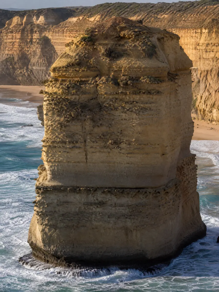 A single limestone stack rising from white surf below the cliffs of Port Campbell National Park