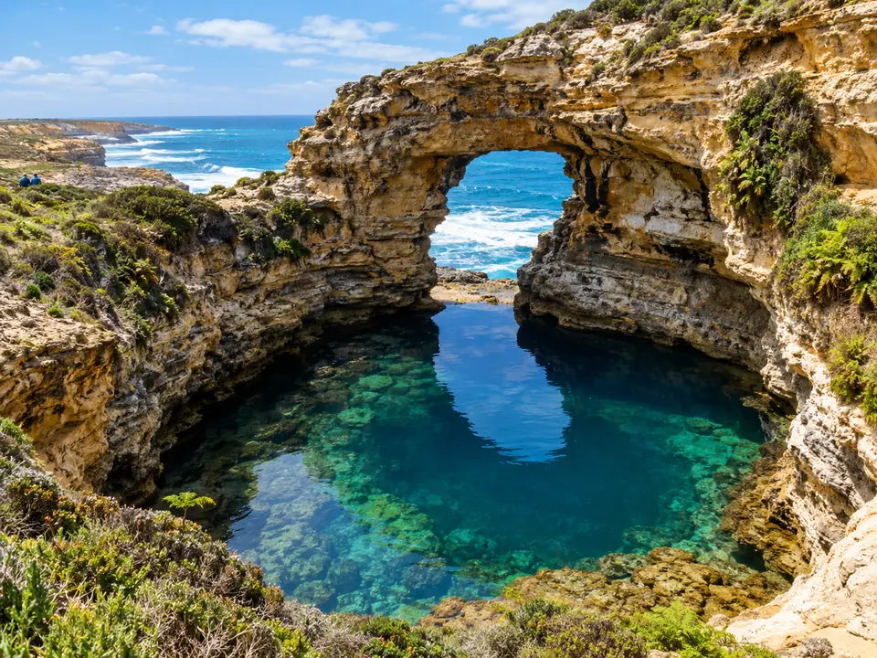 A rock pool framed by an arch in a limestone sinkhole
